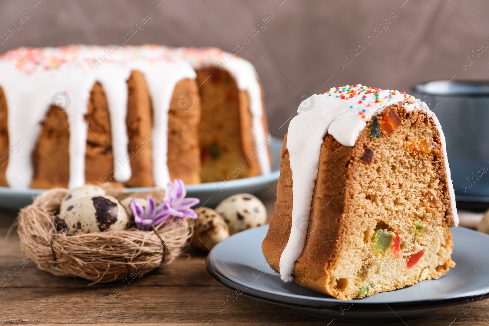 Photo of Piece of glazed Easter cake with sprinkles and candied fruits on wooden table, space for text