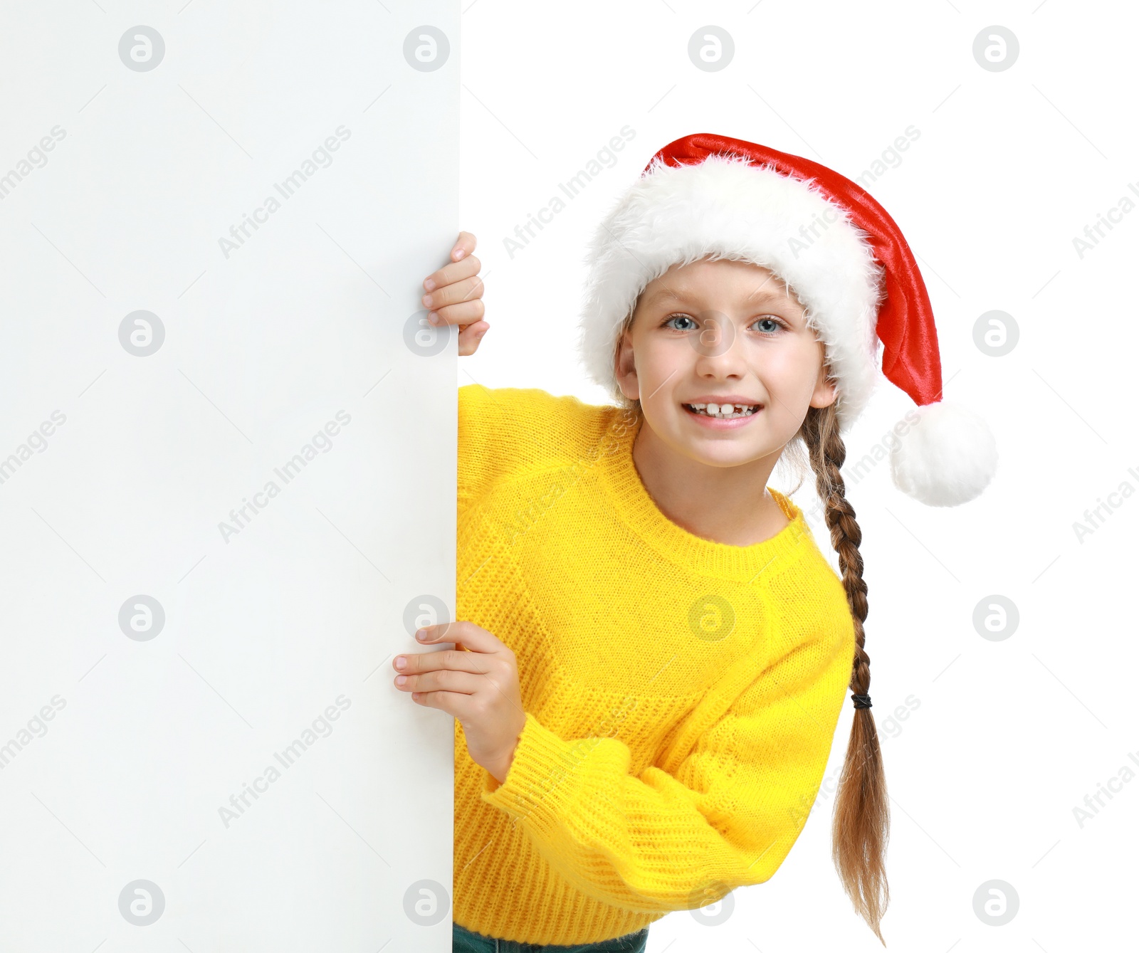 Photo of Happy child in Santa hat peeping out of blank banner on white background. Christmas celebration