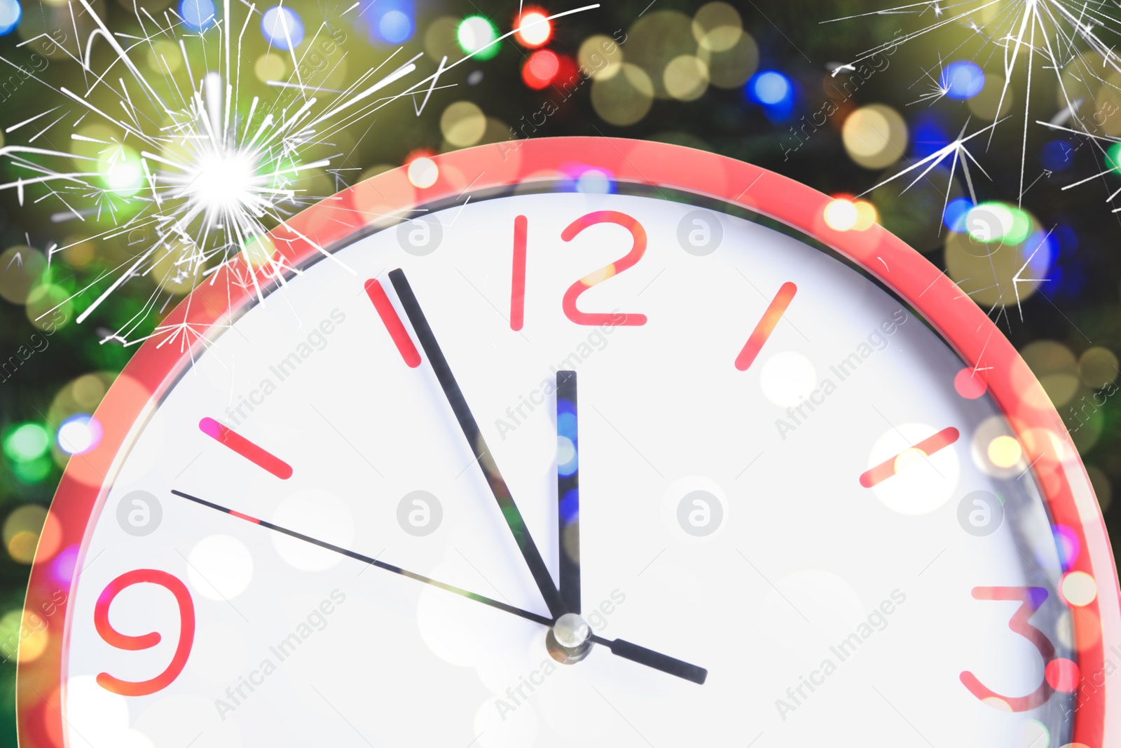 Image of Clock showing five minutes till midnight with sparklers, closeup with bokeh effect. New Year countdown