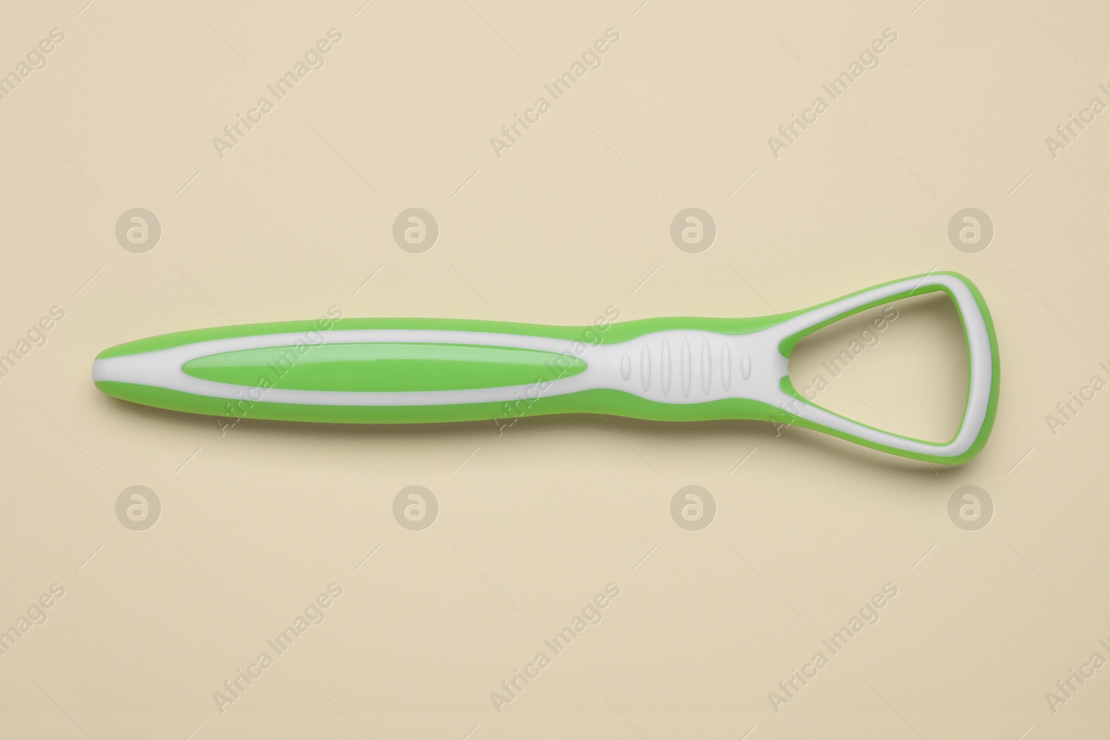 Photo of Green tongue cleaner on beige background, top view