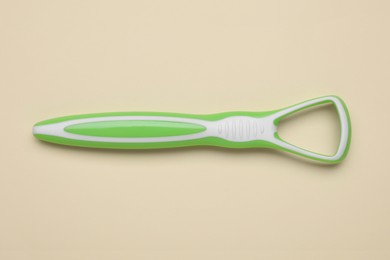 Photo of Green tongue cleaner on beige background, top view