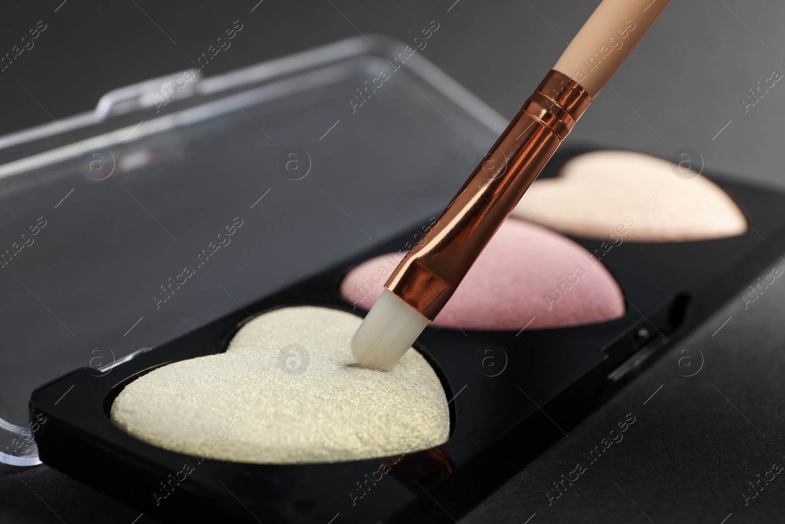 Photo of Palette of heart shaped eyeshadows with brush on dark background, closeup