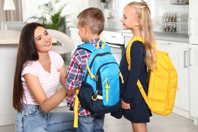 Happy mother and little children with school bags in kitchen