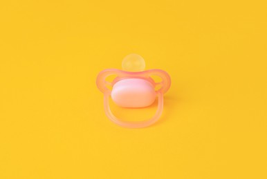 Photo of One new baby pacifier on orange background