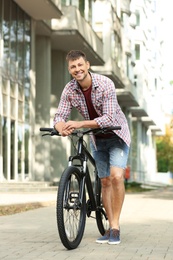 Handsome man with modern bicycle on city street