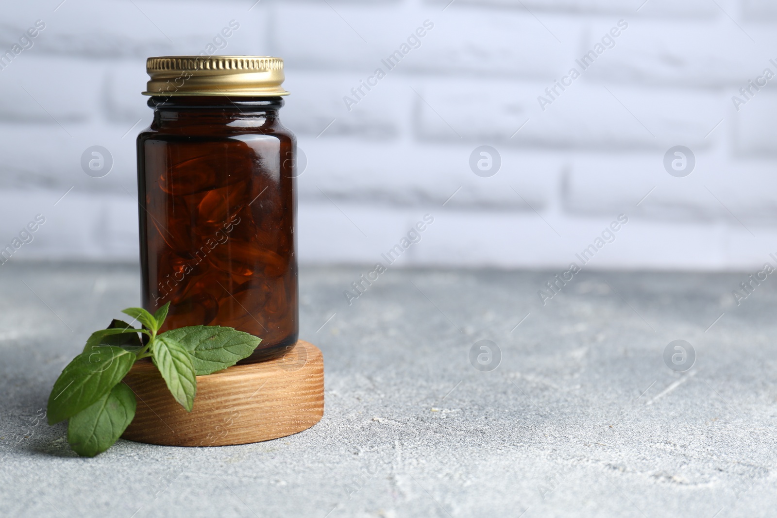 Photo of Medical bottle and mint on light gray textured table, space for text