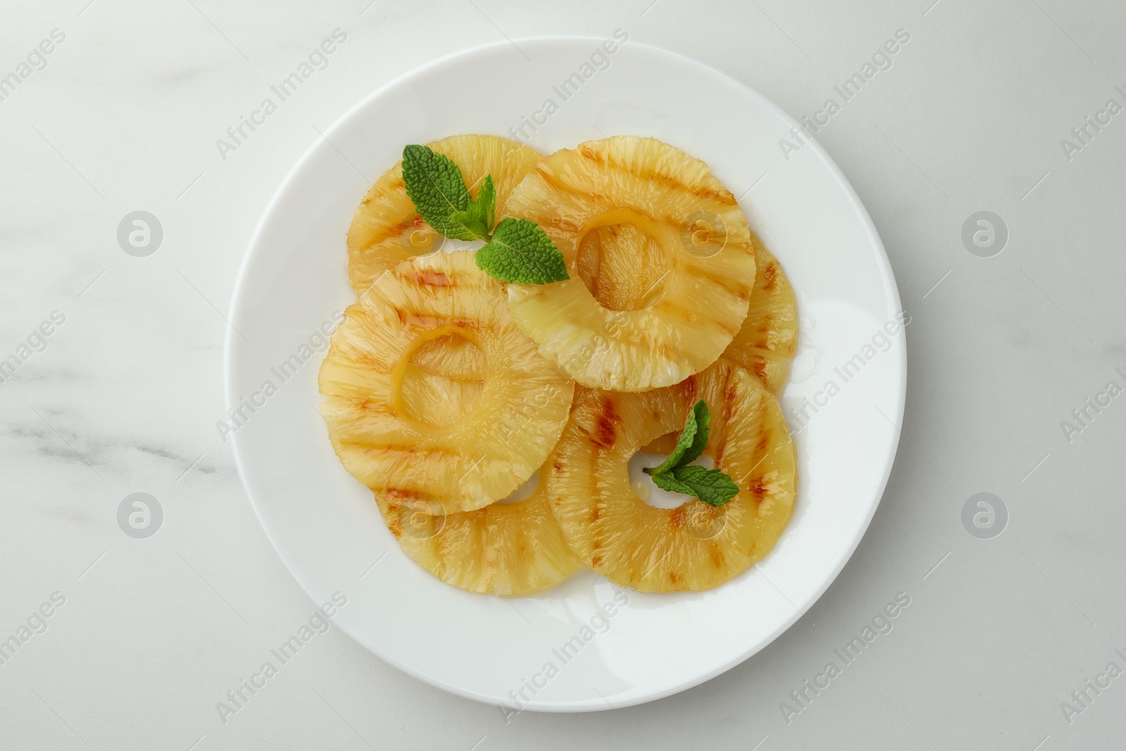 Photo of Tasty grilled pineapple slices with mint on white table, top view