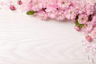 Photo of Beautiful sakura tree blossoms on white wooden background, flat lay. Space for text