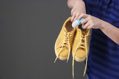 Woman putting capsule shoe freshener in footwear on color background, closeup