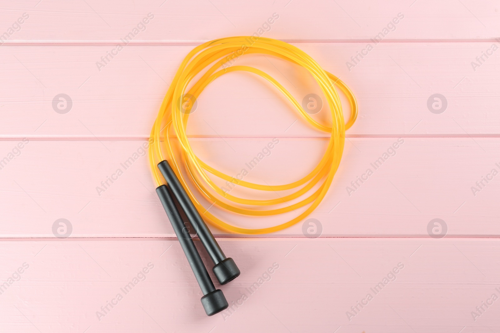 Photo of Skipping rope on pink wooden table, top view. Sports equipment