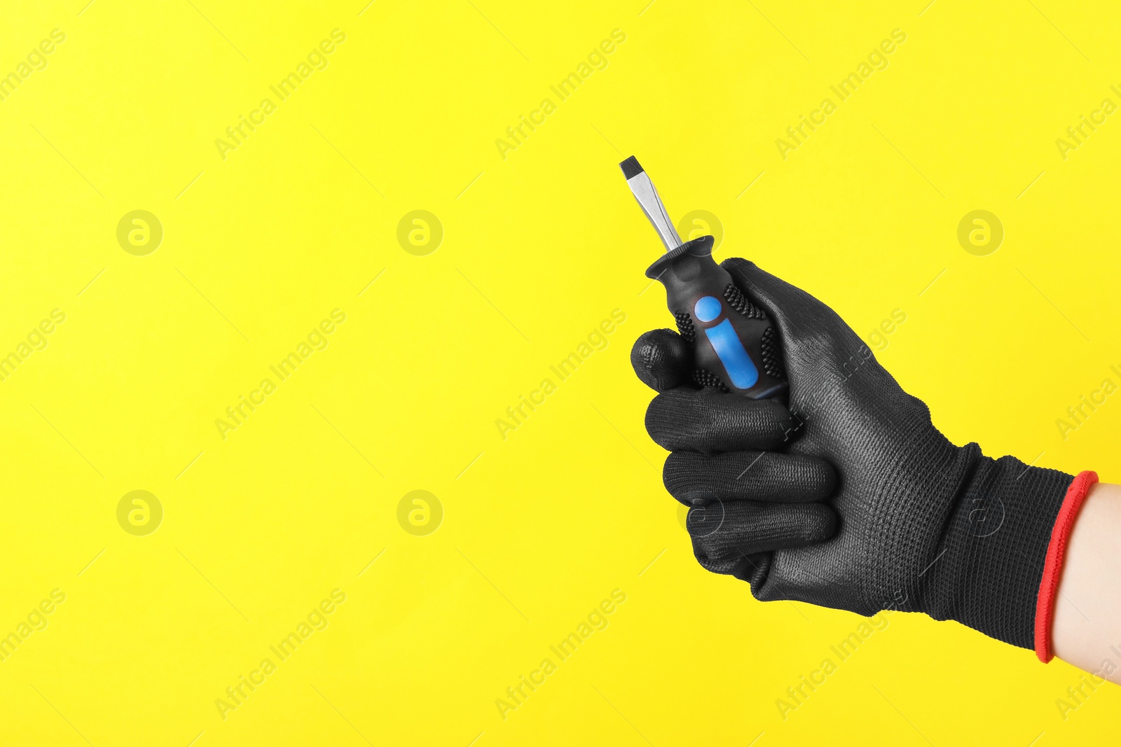 Photo of Woman holding small screwdriver on yellow background, closeup. Space for text