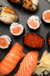 Photo of Set of delicious sushi rolls on slate board, top view