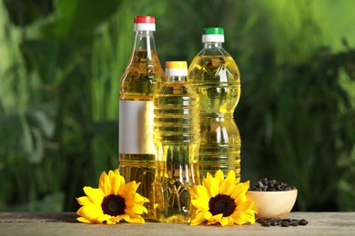 Photo of Bottles of cooking oil, sunflowers and seeds on wooden table against blurred background