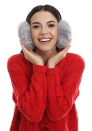 Beautiful young woman wearing earmuffs on white background