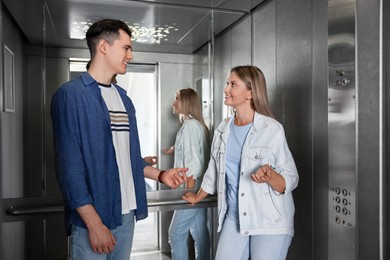 Photo of Happy young people talking in modern elevator