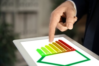 Image of Energy efficiency rating on tablet display. Man using device indoors, closeup