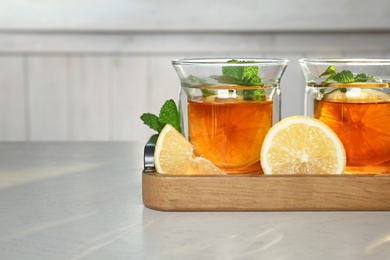 Photo of Wooden tray with hot tea in glasses on table, closeup