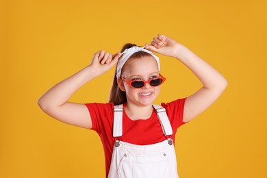 Photo of Cute indie girl with sunglasses on yellow background