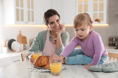 Photo of Mother and her little daughter having breakfast together in kitchen