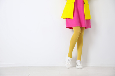 Photo of Woman wearing yellow tights near white wall, closeup. Space for text