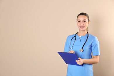 Young medical student with clipboard on color background. Space for text