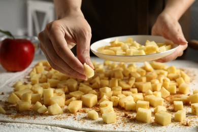 Woman making delicious apple strudel at table, closeup