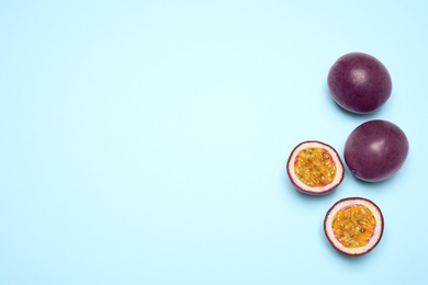 Fresh ripe passion fruits (maracuyas) on light blue background, flat lay. Space for text