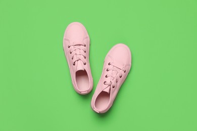 Photo of Pair of comfortable sports shoes on light green background, flat lay