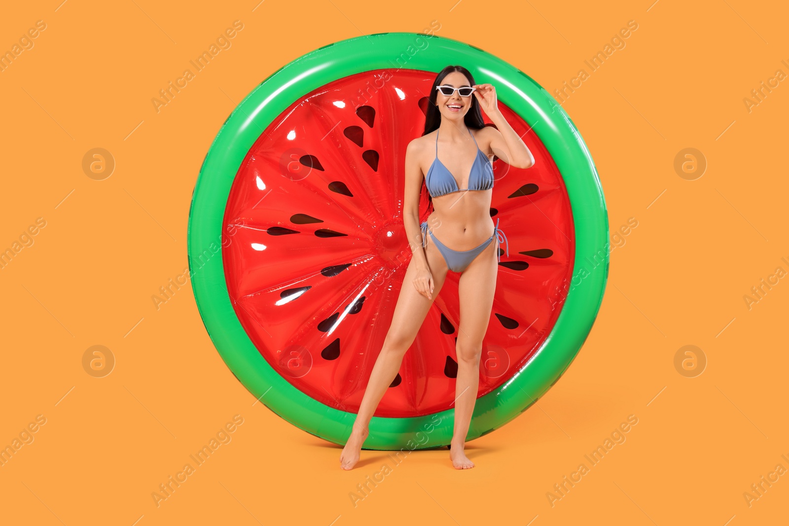 Photo of Happy young woman with beautiful suntan, sunglasses and inflatable mattress against orange background