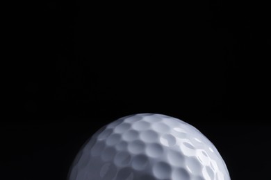 Photo of Golf ball on black background, closeup. Space for text