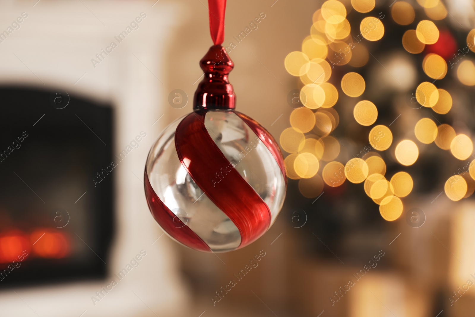 Photo of Beautiful holiday ornament hanging against blurred Christmas lights