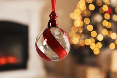 Photo of Beautiful holiday ornament hanging against blurred Christmas lights