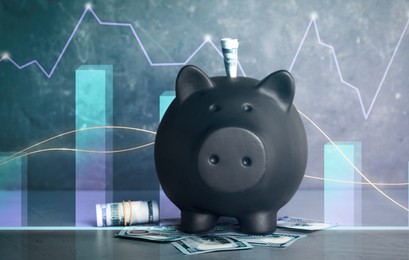 Image of Black piggy bank with money on grey table. Illustration of financial graphs