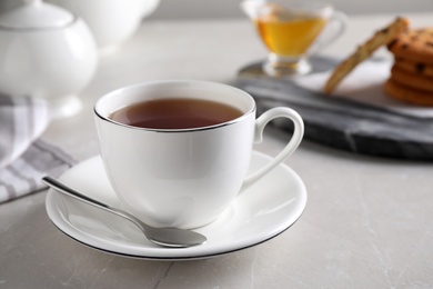Photo of Cup of hot tea and spoon on light grey table