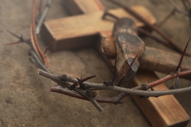 Crown of thorns, wooden cross and hammer on ground, closeup. Easter attributes