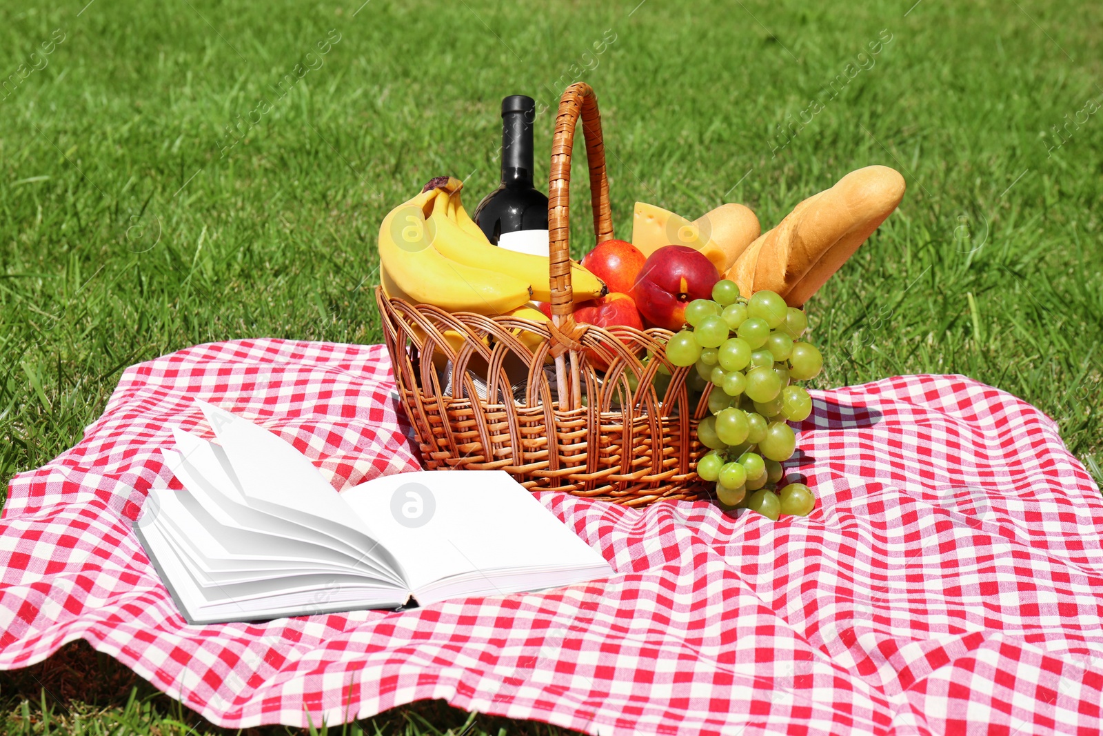 Photo of Basket with food on blanket prepared for picnic in park