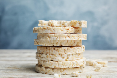 Photo of Stack of puffed rice cakes on white wooden table against light blue background