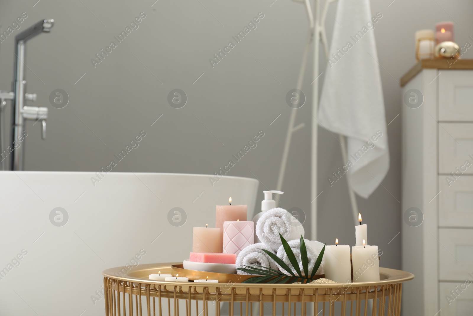 Photo of Stylish bathroom interior with ceramic tub and spa products on table