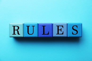 Photo of Word Rules made of wooden cubes with letters on light blue background, flat lay