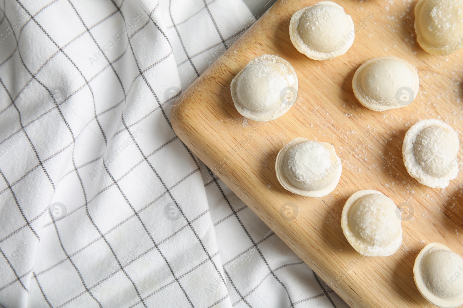 Photo of Board with raw dumplings on napkin, top view. Space for text