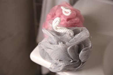 Photo of Colorful shower puffs on washbasin in bathroom, closeup