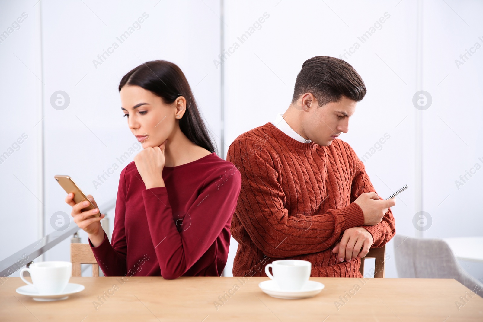 Photo of Couple addicted to smartphones ignoring each other in cafe. Relationship problems