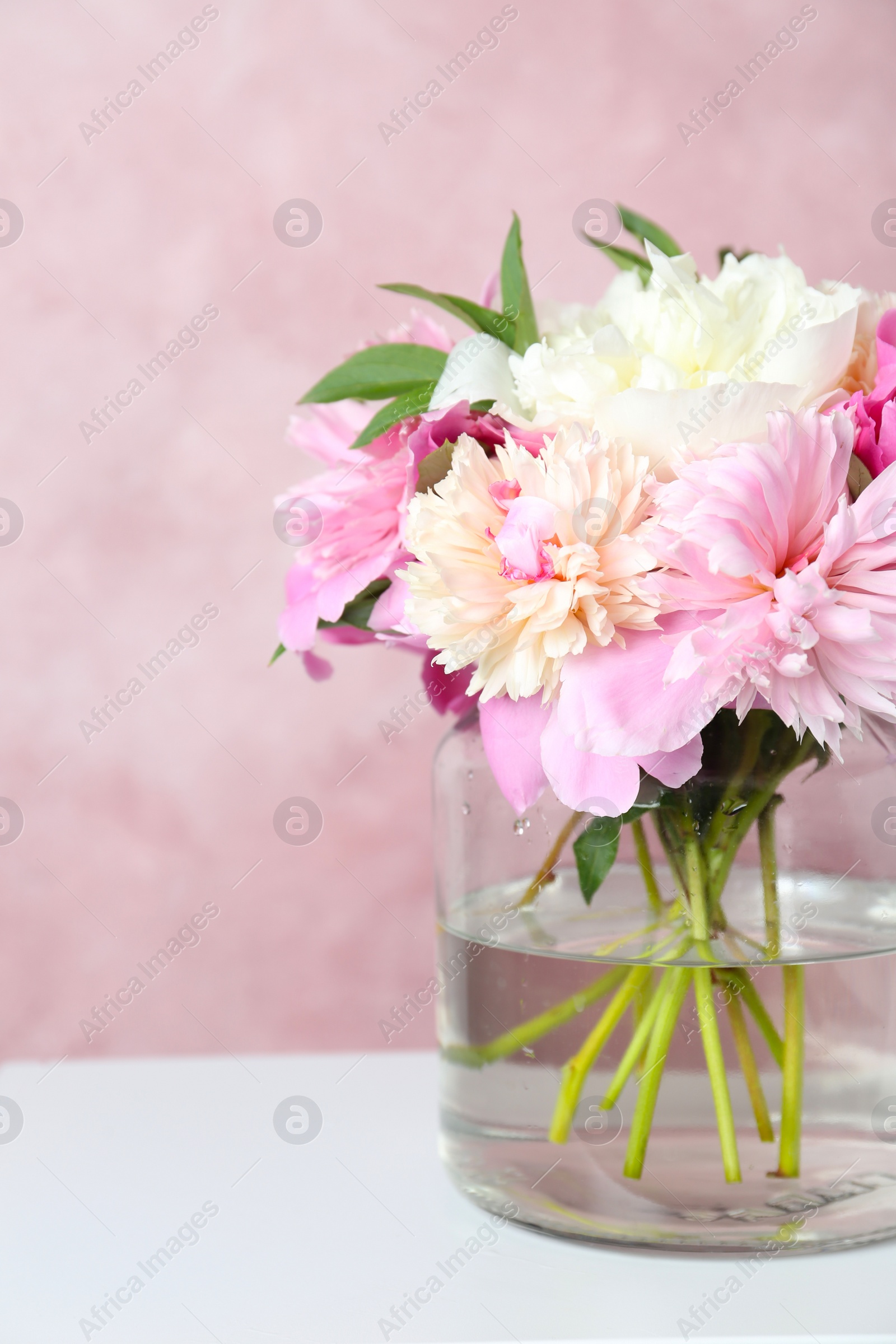 Photo of Bouquet of beautiful peonies in vase on white table