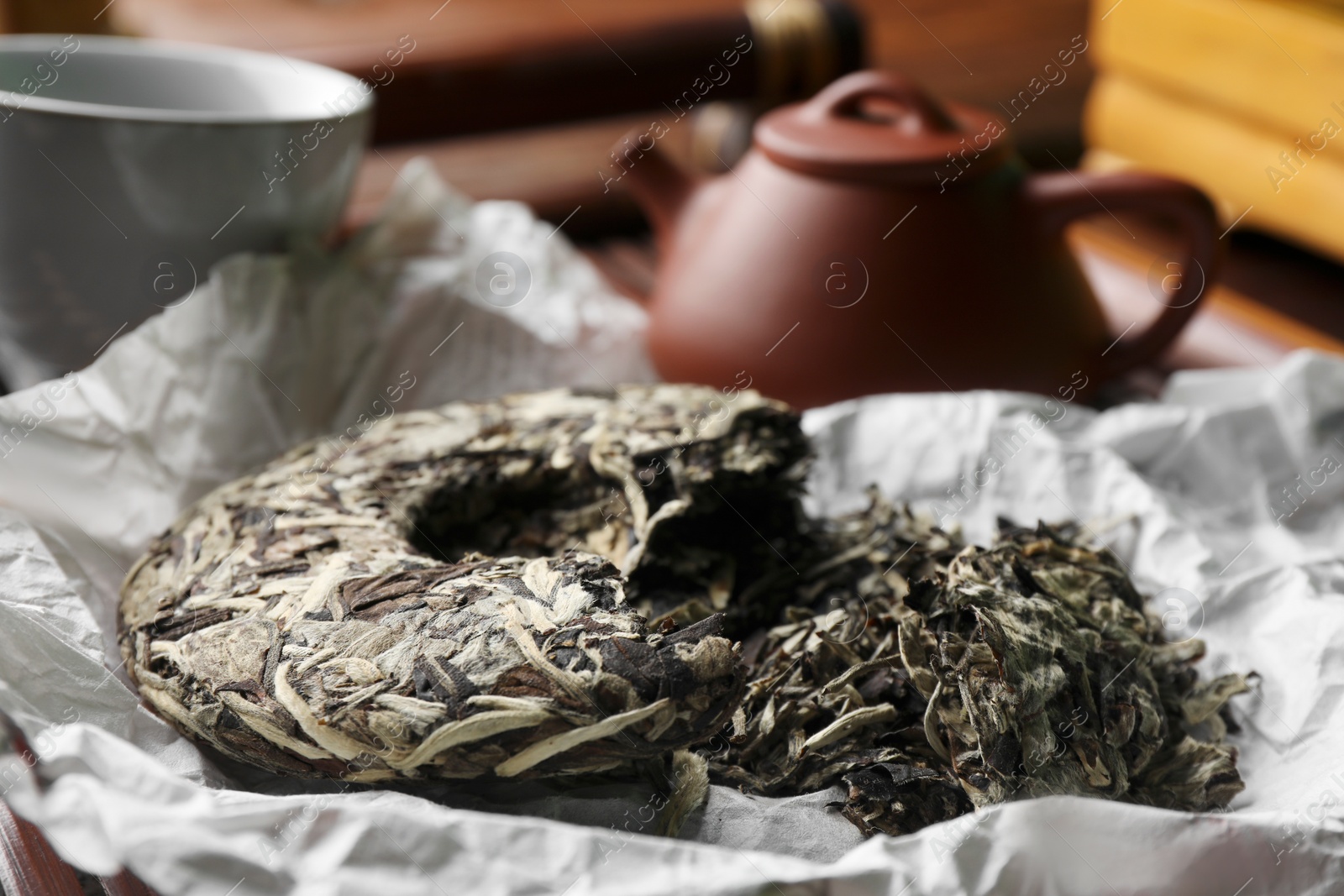 Photo of Broken disc shaped pu-erh tea on parchment paper, closeup. Traditional ceremony