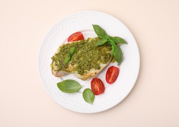 Photo of Delicious chicken breast with pesto sauce, tomatoes and basil on beige table, top view