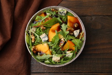 Tasty salad with persimmon, blue cheese and walnuts served on wooden table, top view