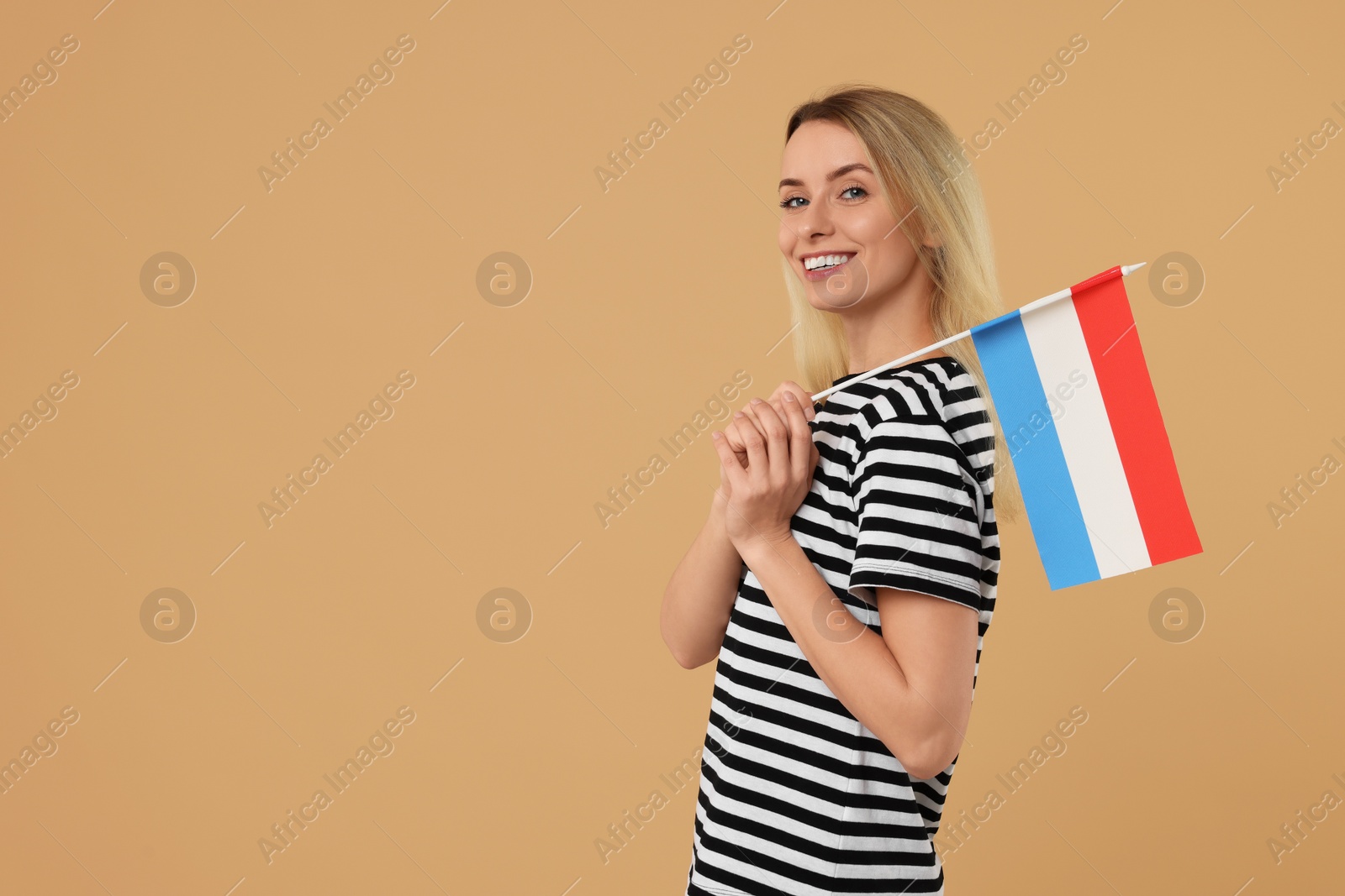 Photo of Happy woman with flag of Netherlands on beige background, space for text