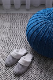 Stylish blue pouf and slippers on floor in room