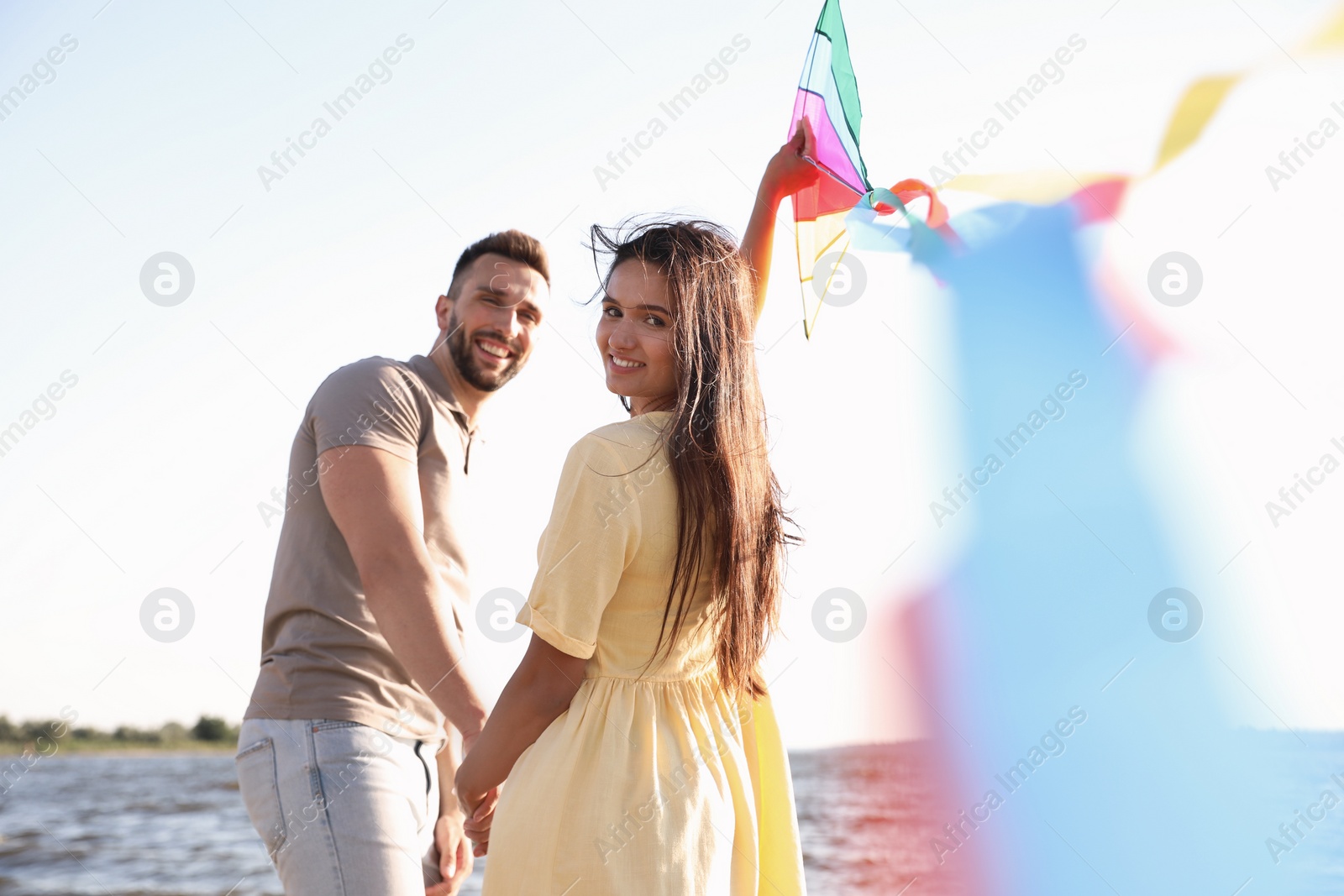 Photo of Happy couple playing with kite near sea. Spending time in nature