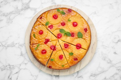 Photo of Delicious cut pineapple pie with cherry and mint on white marble table, top view